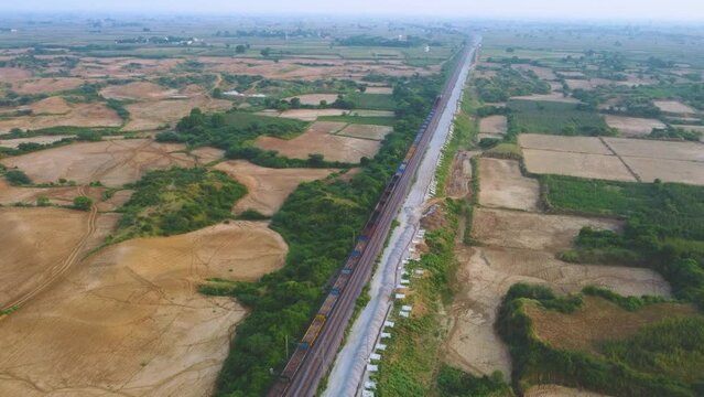 Aerial Drone shot of a Freight train moving through farmlands in Morena India