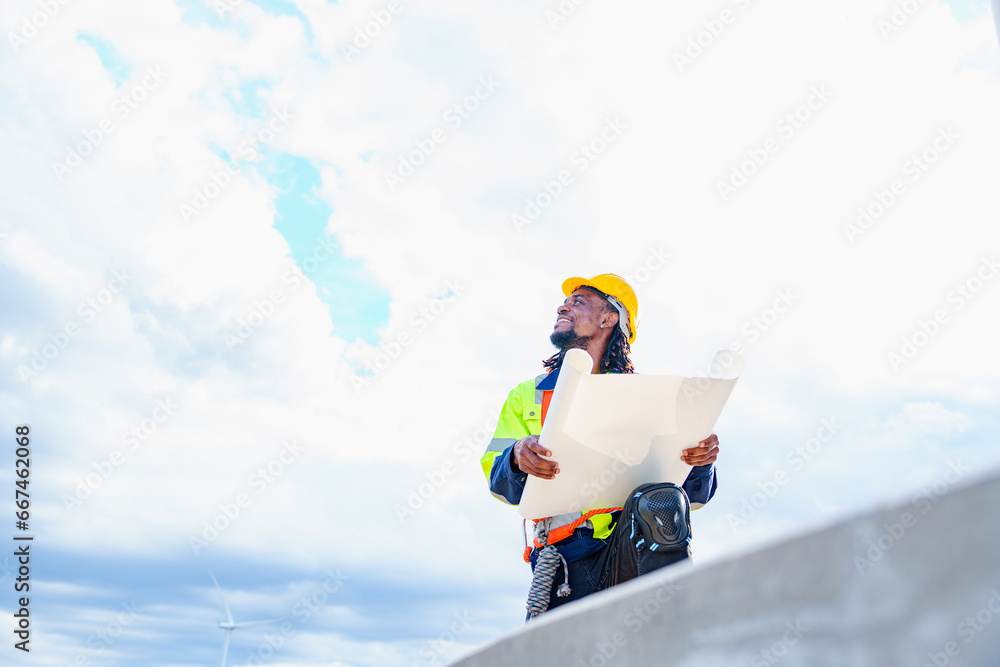 Wall mural Technician engineer African man worker builders looking for wind turbine blueprint drawings for wind turbine construction at windmill field farm. Alternative renewable energy for clean energy concept. - Wall murals