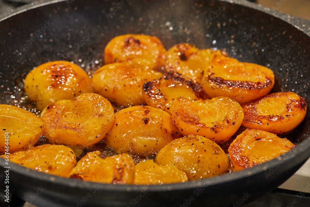 Sticker Halves of fresh apricots are fried in caramel syrup in frying pan on gas stove