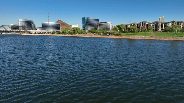 Tempe skyline overlooking Tempe Town Lake and Salt River. Aerial glide above water on beautiful afternoon with blue sky. Establishing shot of Tempe, Arizona.