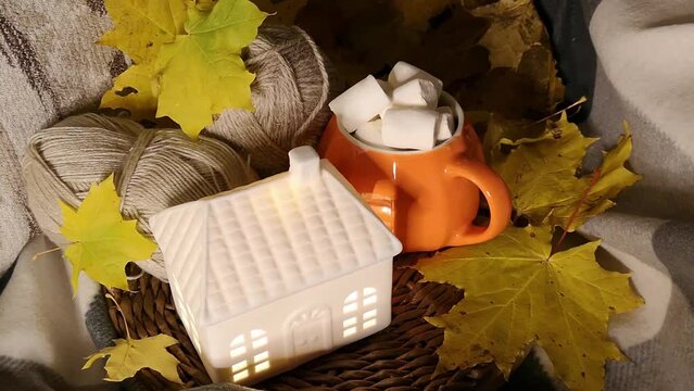 Cozy autumn. Hygge atmosphere. A beautiful concept for celebrating Halloween or Thanksgiving. Autumn leaves, sweets and a candle on a cozy blanket. Autumn still life with a candle. Autumn crafts