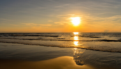 Obraz premium The sun is low over the water on the sea beach