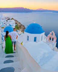 A couple of men and woman on vacation in Greece visited the village of Oia Santorini during sunset,...