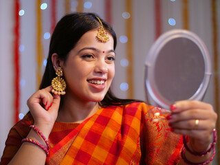 A closeup shot of a beautiful Indian girl swinging her traditional earrings - festive mood  diwali vibe. Pretty Indian woman getting ready for Diwali festival - festival of lights