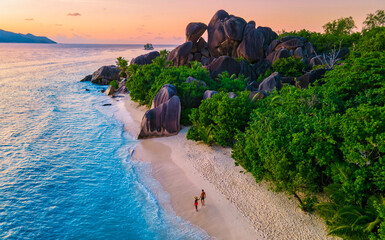 Anse Source d'Argent beach, La Digue Island, Seychelles, aerial view of La Digue Seychelles a tropical Island, couple men and woman walking at the beach during sunset at a luxury vacation