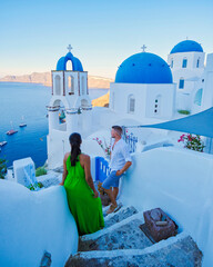 a couple of men and women on vacation in Santorini Greece. young couple on vacation in Greece Santorini watching the sunrise over the ocean at the narrow streets of the village of Oia  - obrazy, fototapety, plakaty