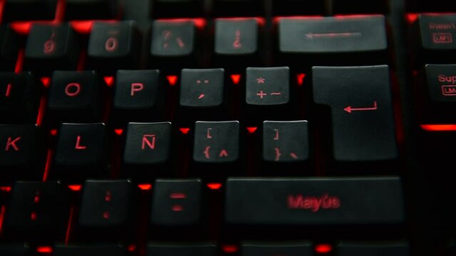 Man's hand pressing the ENTER key on a red backlit black computer keyboard. selective focus.