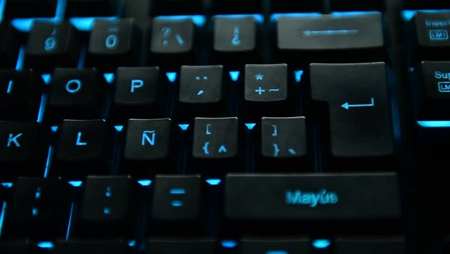 Man's hand pressing the ENTER key on a sky blue backlit black computer keyboard. selective focus.