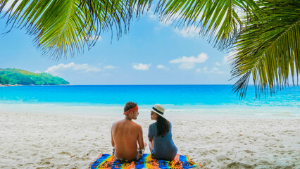 Couple relaxing under a palm tree on a white tropical beach Anse Lazio Praslin Tropical Seychelles...