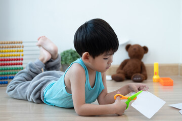 Asian boy using scissors to cut paper along lines Learning outside the classroom