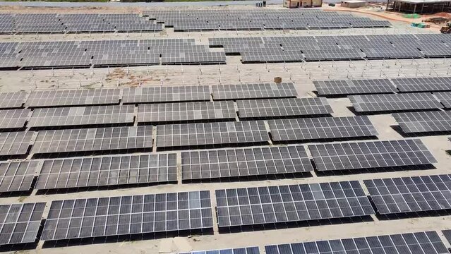 Aerial forward flying over dirty dusty bifacial solar panels at Jambur solar photovoltaic energy project site under construction in Gambia