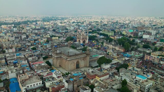 aerial view of charminar and mecca masjid surrounded by buildings and eagle flying in old city, hyderabad, telangana