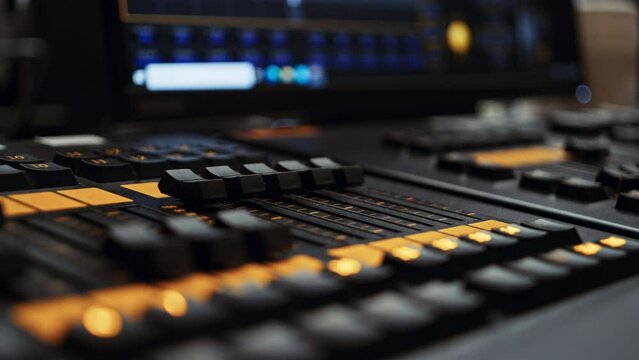 Two edge faders of a professional dmx lighting control desk console panel being turned up, making lights brighter. Light console used in film or tv production, broadcast or live music event production