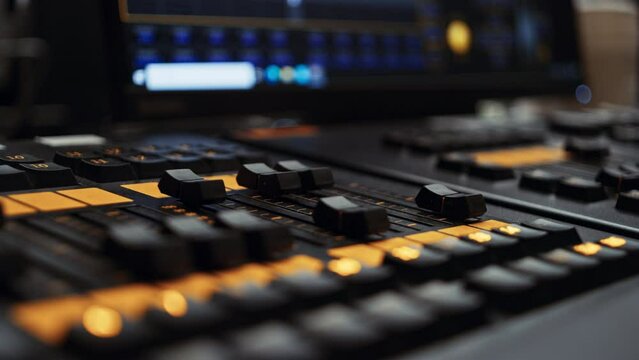 Two center faders of a professional dmx lighting control desk console panel being turned up, making lights brighter. Light console used in film, broadcast or live music event production