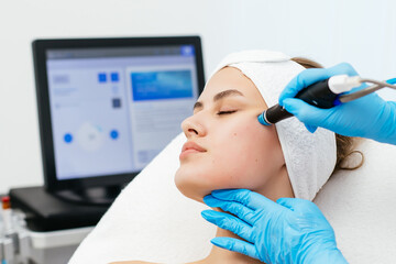 Close-up shot of a young beautiful woman lying on a couch in a cosmetology center. Young woman doing hydrofacial therapy in beauty spa. - obrazy, fototapety, plakaty