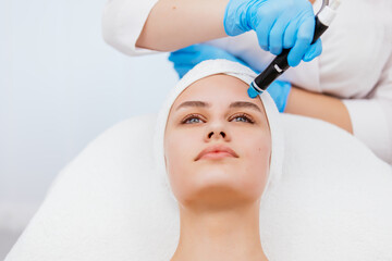 Close-up shot of a young beautiful woman lying on a couch in a cosmetology center. Young woman doing hydrofacial therapy in beauty spa.