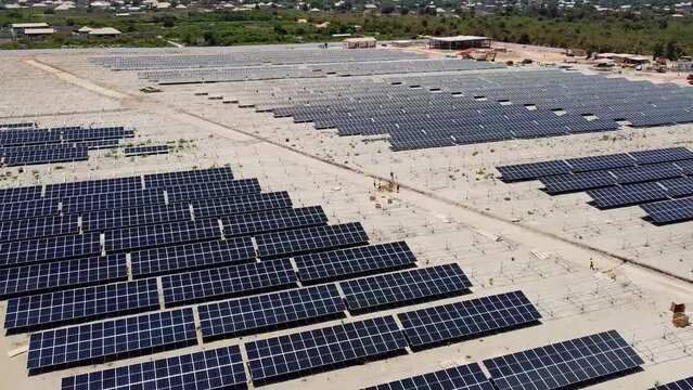 Aerial fly over solar farm with clean, dirty and dusty bifacial solar panels at Jambur Gambia solar photovoltaic project site under construction