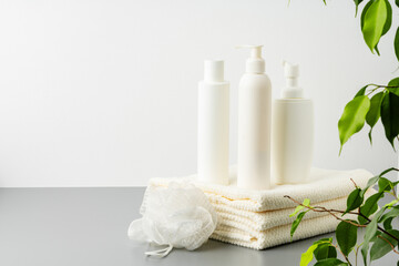 Obraz na płótnie Canvas Set of blank cosmetic bottles and towels on gray background
