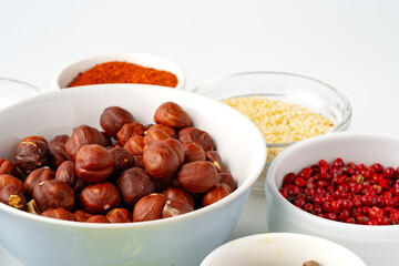 Bowls with spices and cooking ingredients on white background