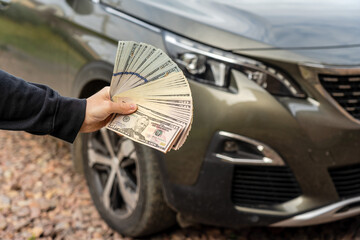 Person with money in the hands standing front car. Insurance, loan concept. Deal of buy or rent new...