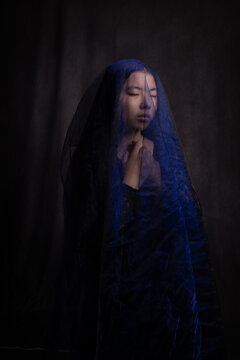 asian girl in black dress and blue veil in painterly portrait in dark style