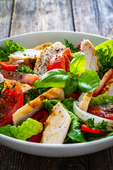 Caesar style salad - grilled chicken breast and fresh vegetables on wooden table