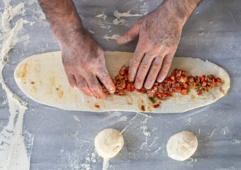Preparing and baking pita kıymalı and kuşbaşılı pide . Hands of a male making meat pizza. 