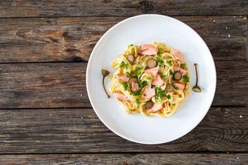 Tagliatelle with salmon and mayonnaise on wooden table
