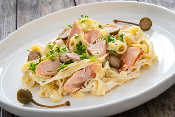 Tagliatelle with salmon and mayonnaise on wooden table
