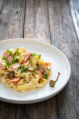 Tagliatelle with salmon and mayonnaise on wooden table

