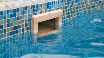 Dirty wall skimmer equipment filtration swimming pool system with reflection on blue water pool....