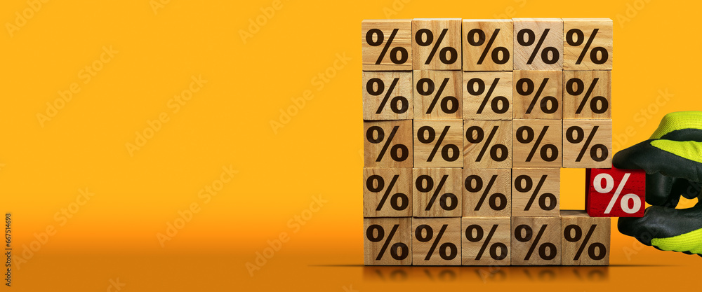 Poster gloved hand chooses a wooden block with red percentage sign, from a stack of wooden blocks with brow