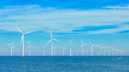 Windmill park in the ocean with a blue sky, drone aerial view of windmill turbines generating green energy, windmills isolated at sea in the Netherlands. 
