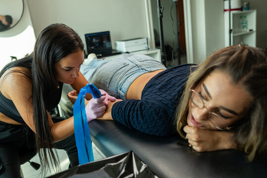 In the tattoo studio's artistic setting, an artist skillfully inks a design onto a client's skin, a fusion of artistry and personal expression.