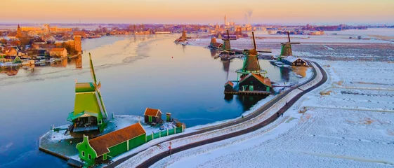 Cercles muraux Amsterdam Zaanse Schans Netherlands a Dutch windmill village during sunrise at winter with a snowy landscape, winter snow at the historical windmill village near Amsterdam