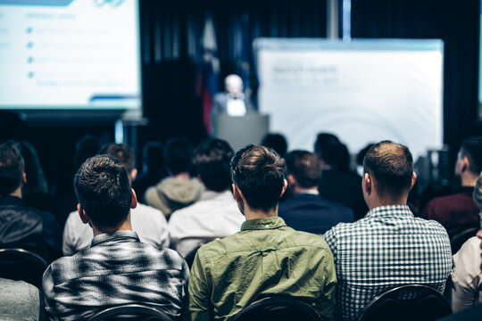 Speaker giving a talk in conference hall at business event. Rear view of unrecognizable people in audience at the conference hall. Business and entrepreneurship concept