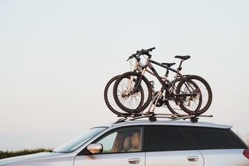 Passenger car with two bicycles mounted to the roof. Roof-mounted bikes. Sports equipment transportation.