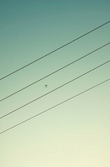 An airplane flying over power lines, resembling musical staff lines.