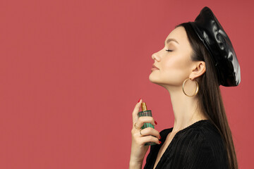 Attractive girl in a hat with perfume in her hand