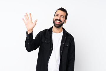 Young man with beard over isolated white background saluting with hand with happy expression