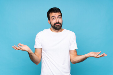Fototapeta premium Young man with beard over isolated blue background having doubts while raising hands
