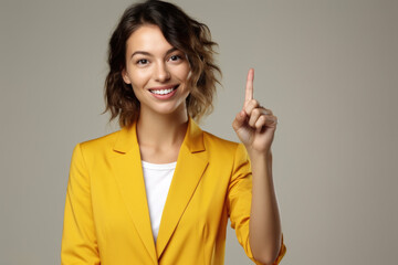 Woman wearing yellow blazer is holding up peace sign with her hand. This image can be used to...