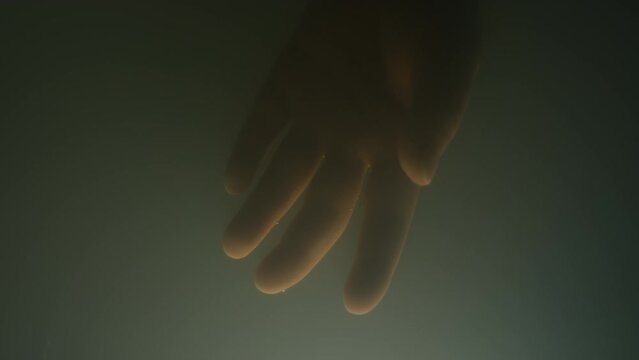Macro close up of unrecognizable lab grown foetus hand in opaque lab made amniotic fluid twirling around in artificial womb