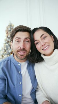 POV Webcam view Vertical video. Happy family couple communicates on a video call at home during winter New Year Christmas Xmas holidays. Smiling wife and husband talking wishes, congratulates remotely