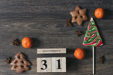 Brown wooden calendar with Christmas tree candy, mandarin, gingerbreads and anis on the dark wooden background. Christmas holidays. Reminder, planner or meeting. 31 December, end of year. New Year.