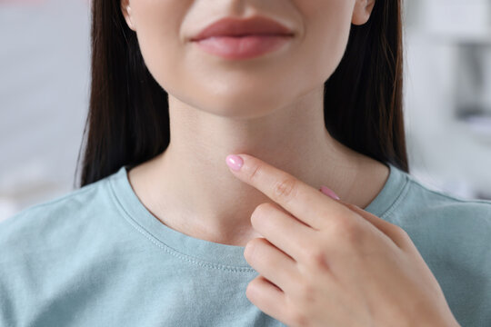 Endocrine system. Woman doing thyroid self examination indoors, closeup