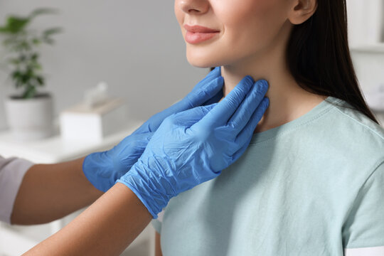 Endocrinologist examining thyroid gland of patient indoors, closeup