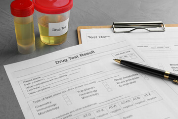 Drug test result form, containers with urine samples and pen on grey table, closeup