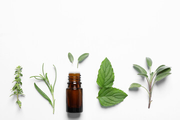 Bottle of essential oil and different herbs on white background, flat lay. Space for text