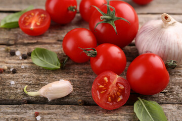 Ripe tomatoes, basil, garlic and spices on wooden table, closeup